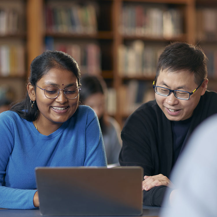 Students on campus in the library reading a book
